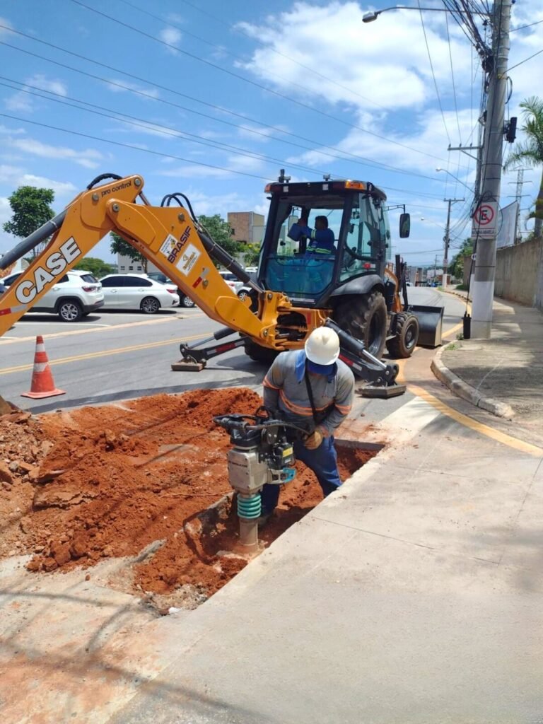 Escavadeira operando em via pavimentada